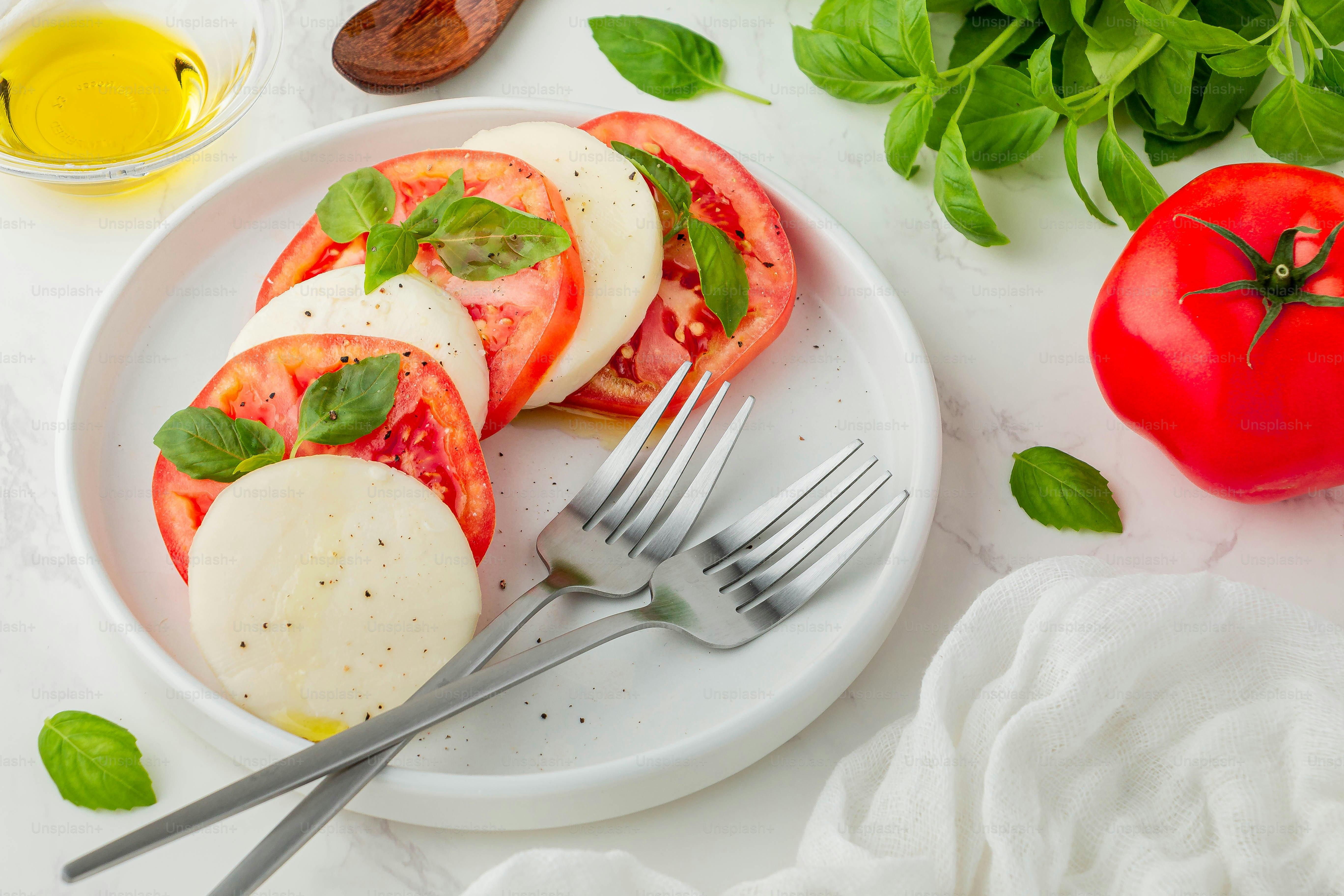 a white plate topped with sliced tomatoes and cheese