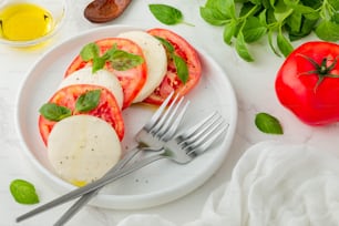 a white plate topped with sliced tomatoes and cheese