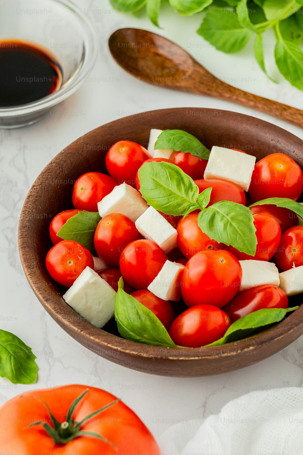 a wooden bowl filled with tomatoes and cheese