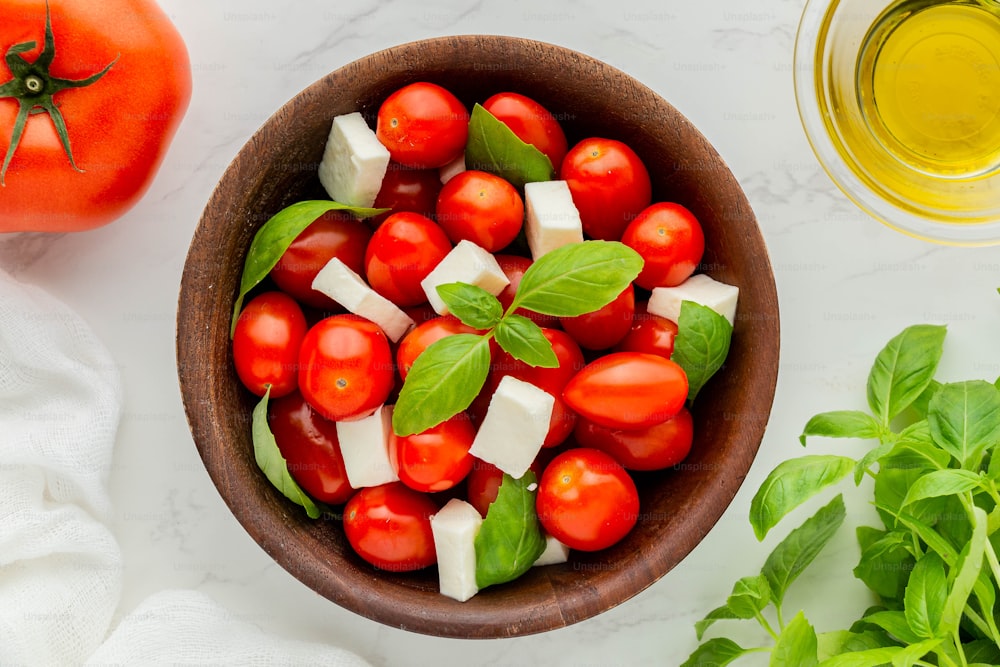 a wooden bowl filled with tomatoes and cheese