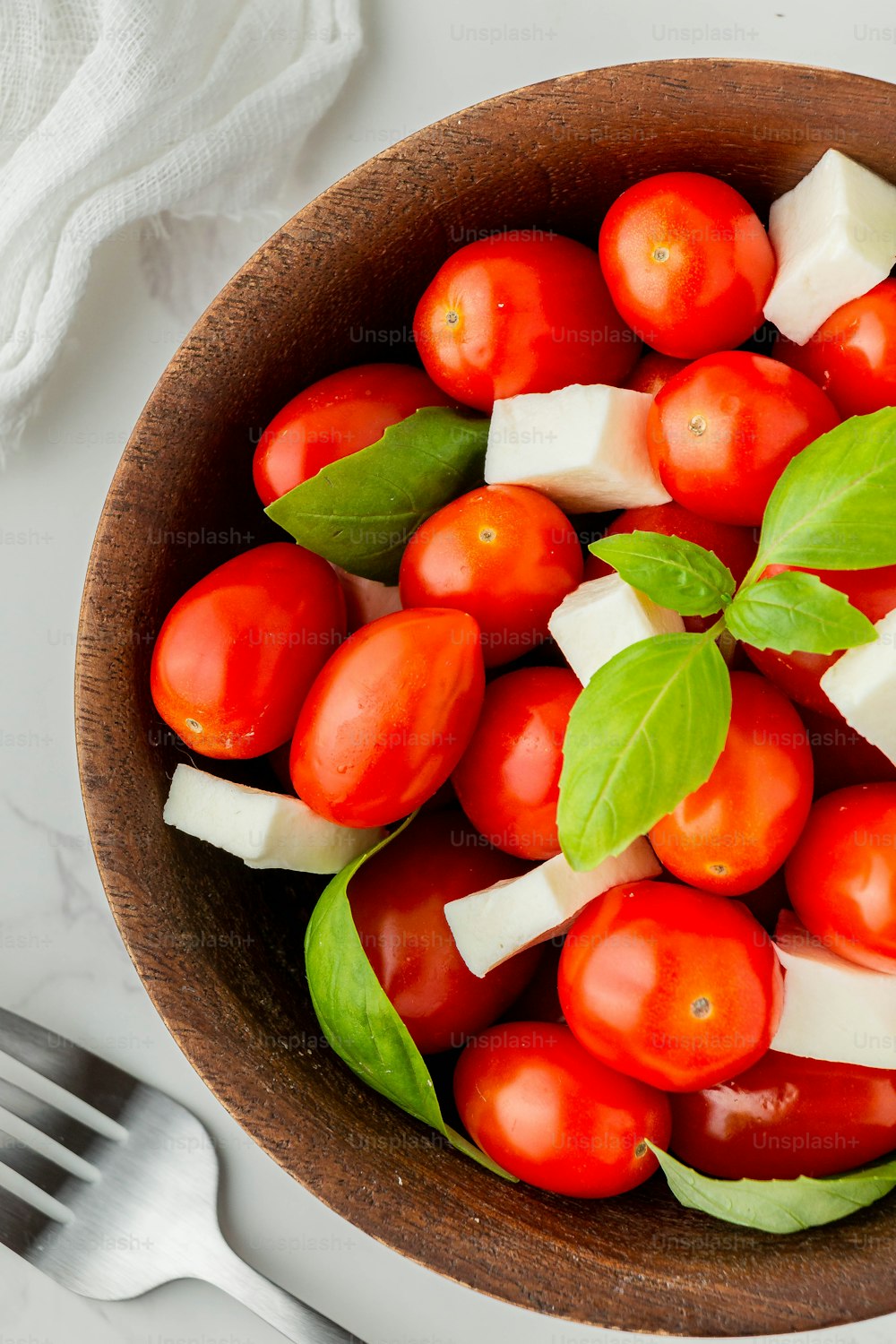 a wooden bowl filled with tomatoes and cheese