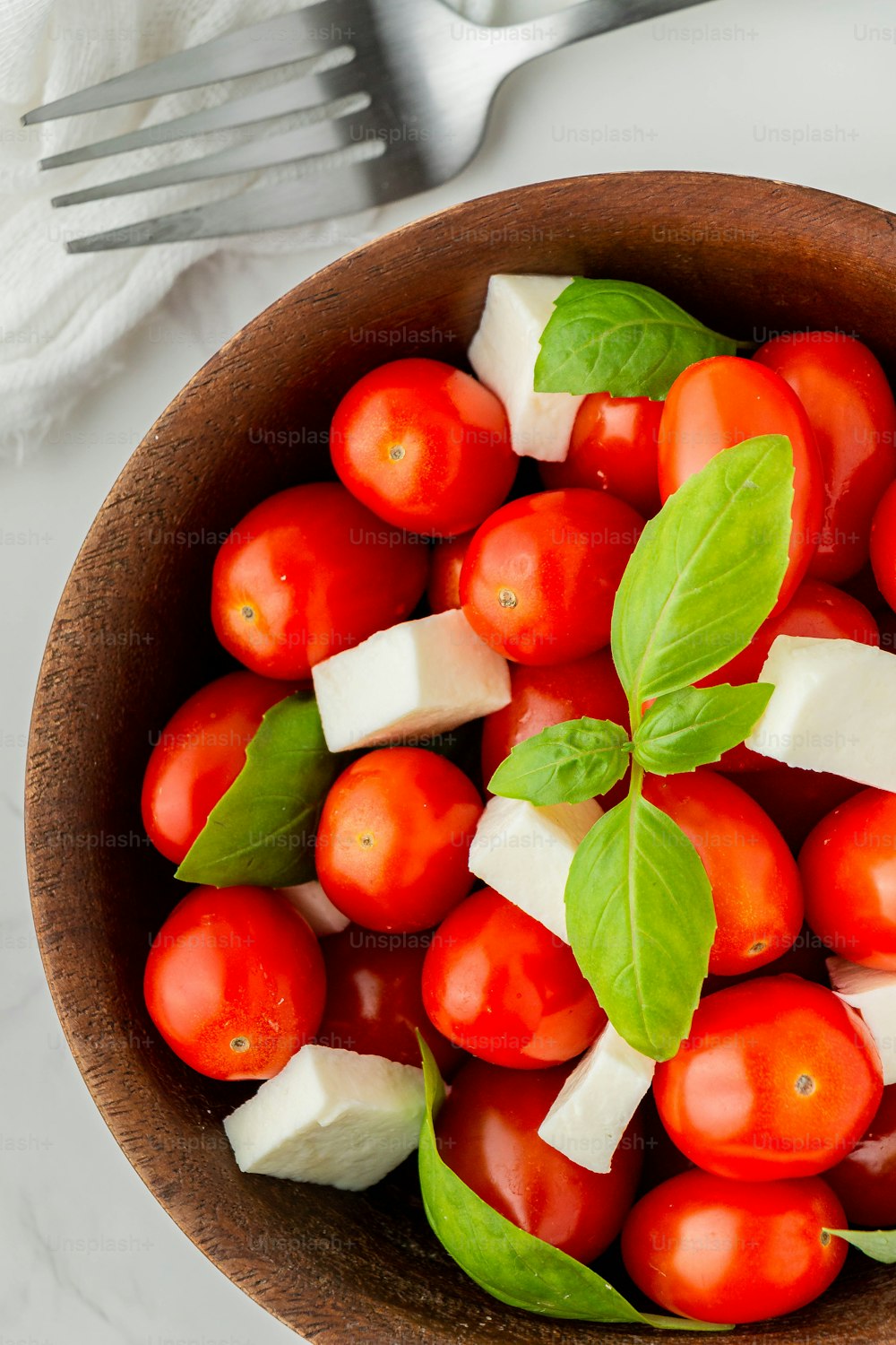 a wooden bowl filled with tomatoes and cheese