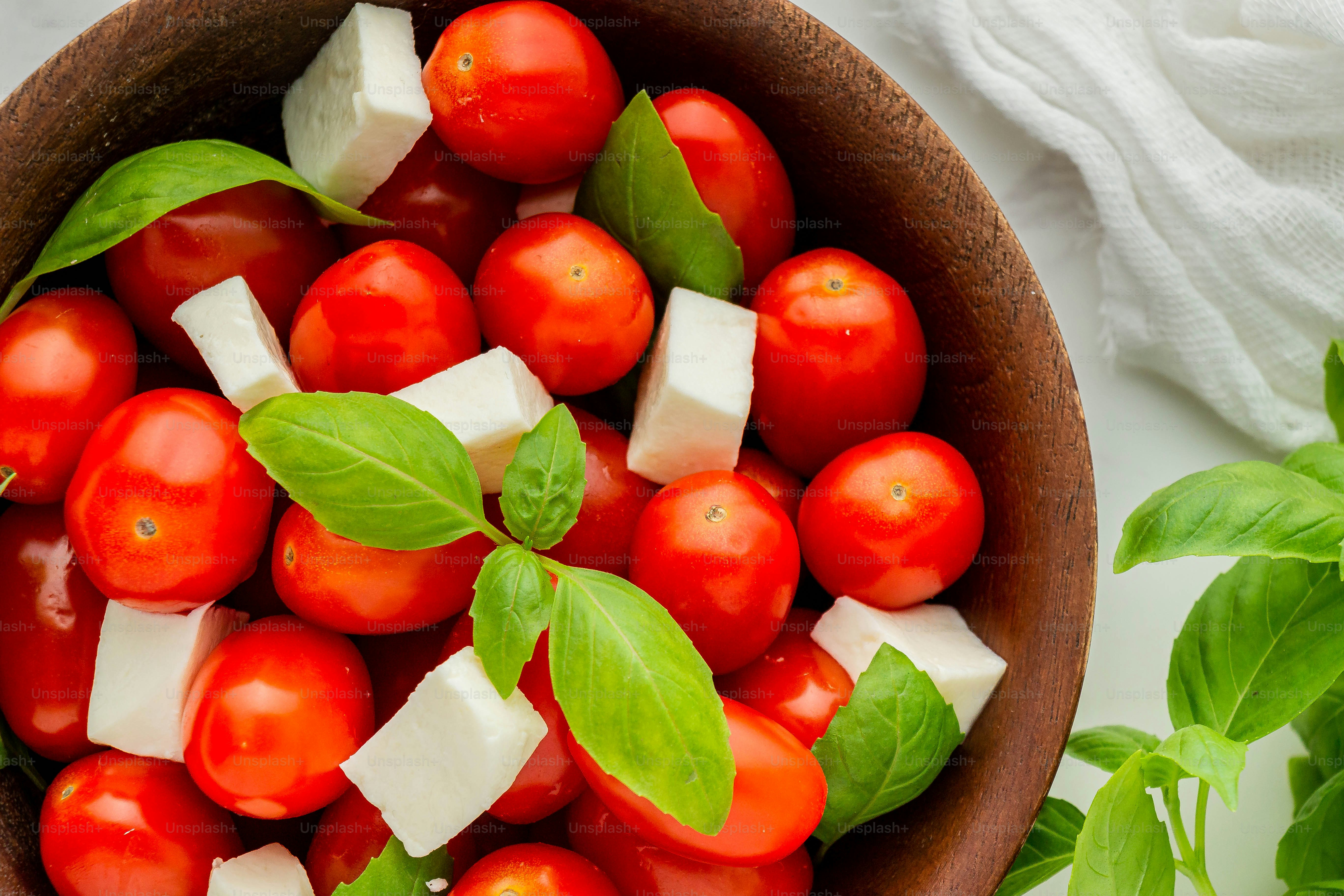 a wooden bowl filled with tomatoes and cheese