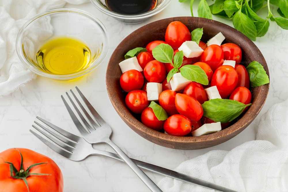 a bowl of tomatoes, mozzarella, basil, and olive oil