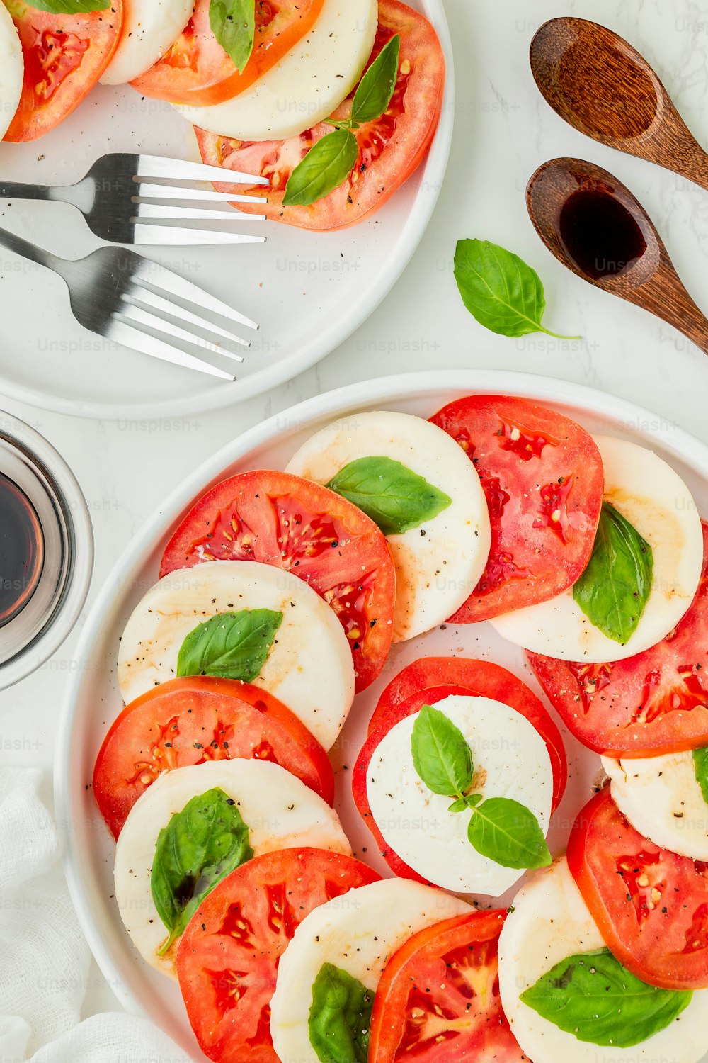 une assiette blanche garnie de tranches de tomates et de basilic