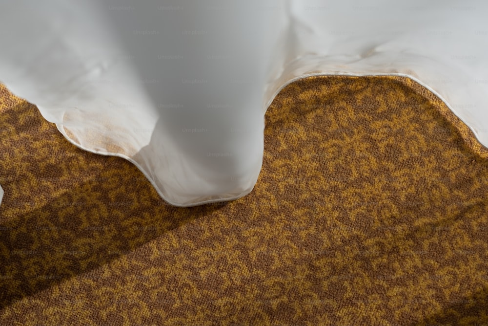 a close up of a white vase on a brown carpet