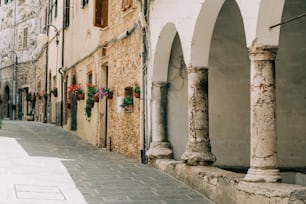 a narrow street with arches and flowers on the wall