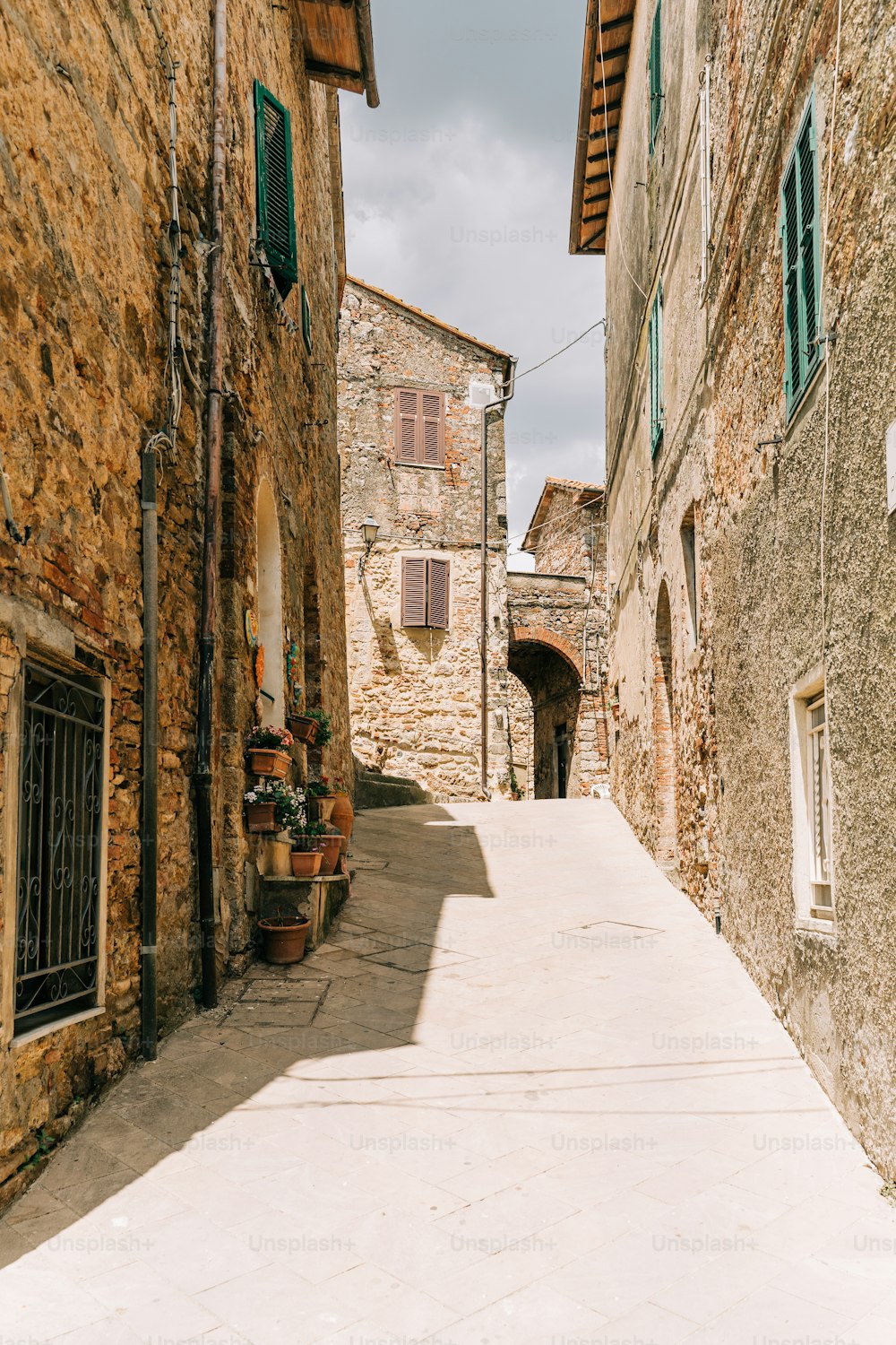 a narrow alley with a stone building and green shutters