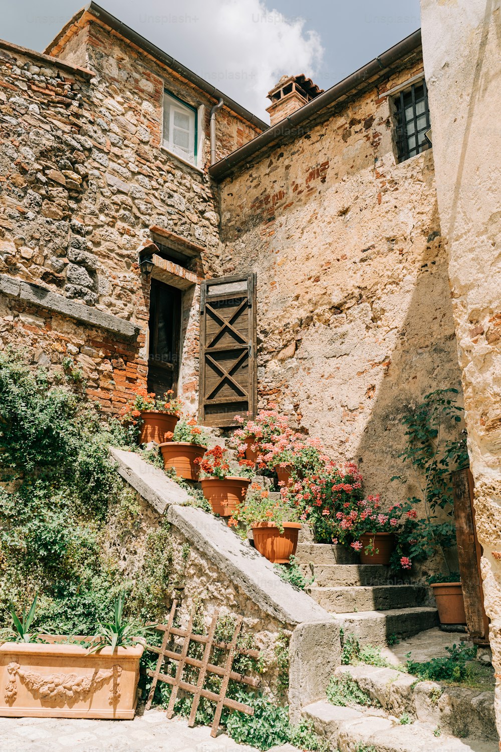 a stone building with potted plants on the steps