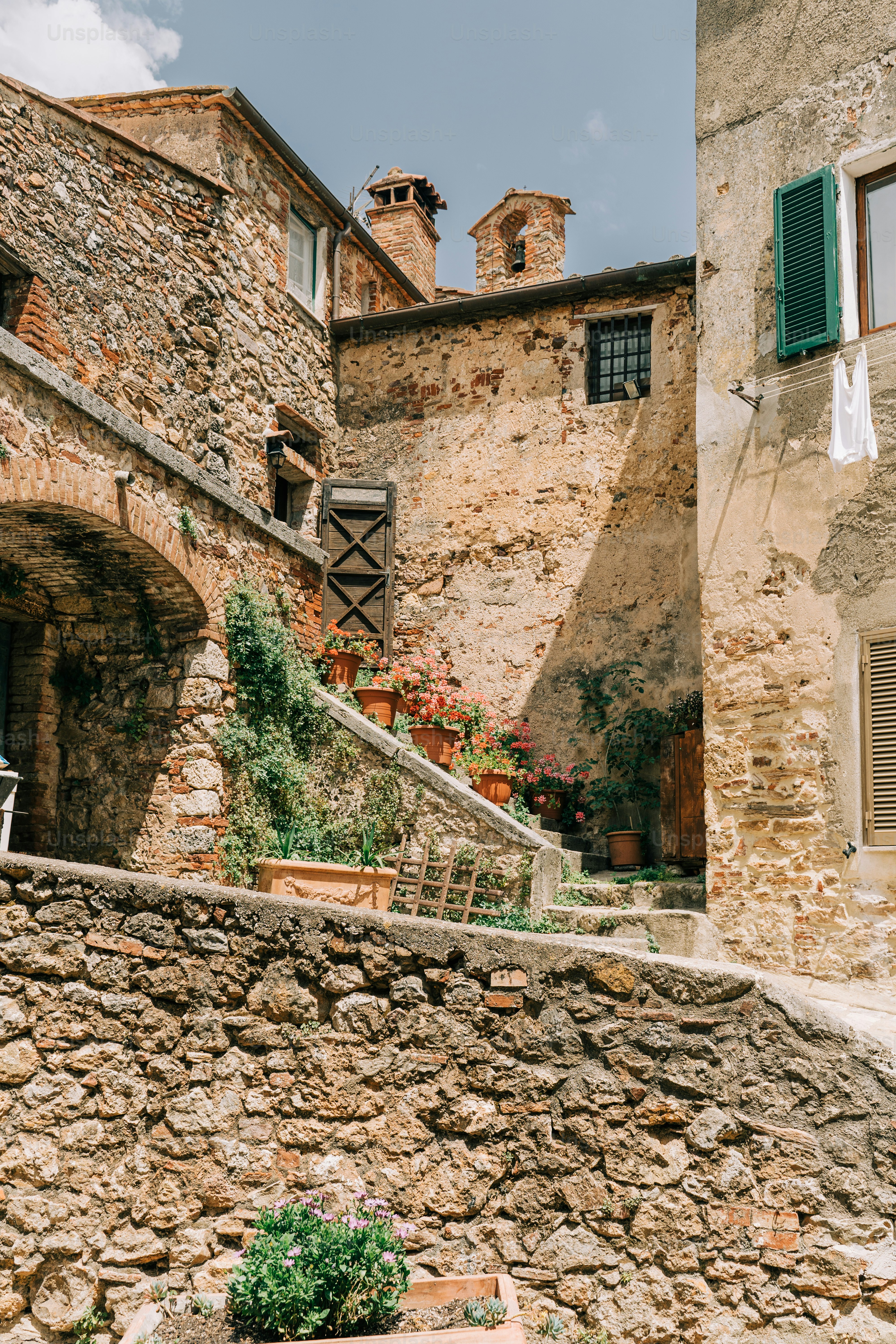 a stone building with green shutters next to a stone wall