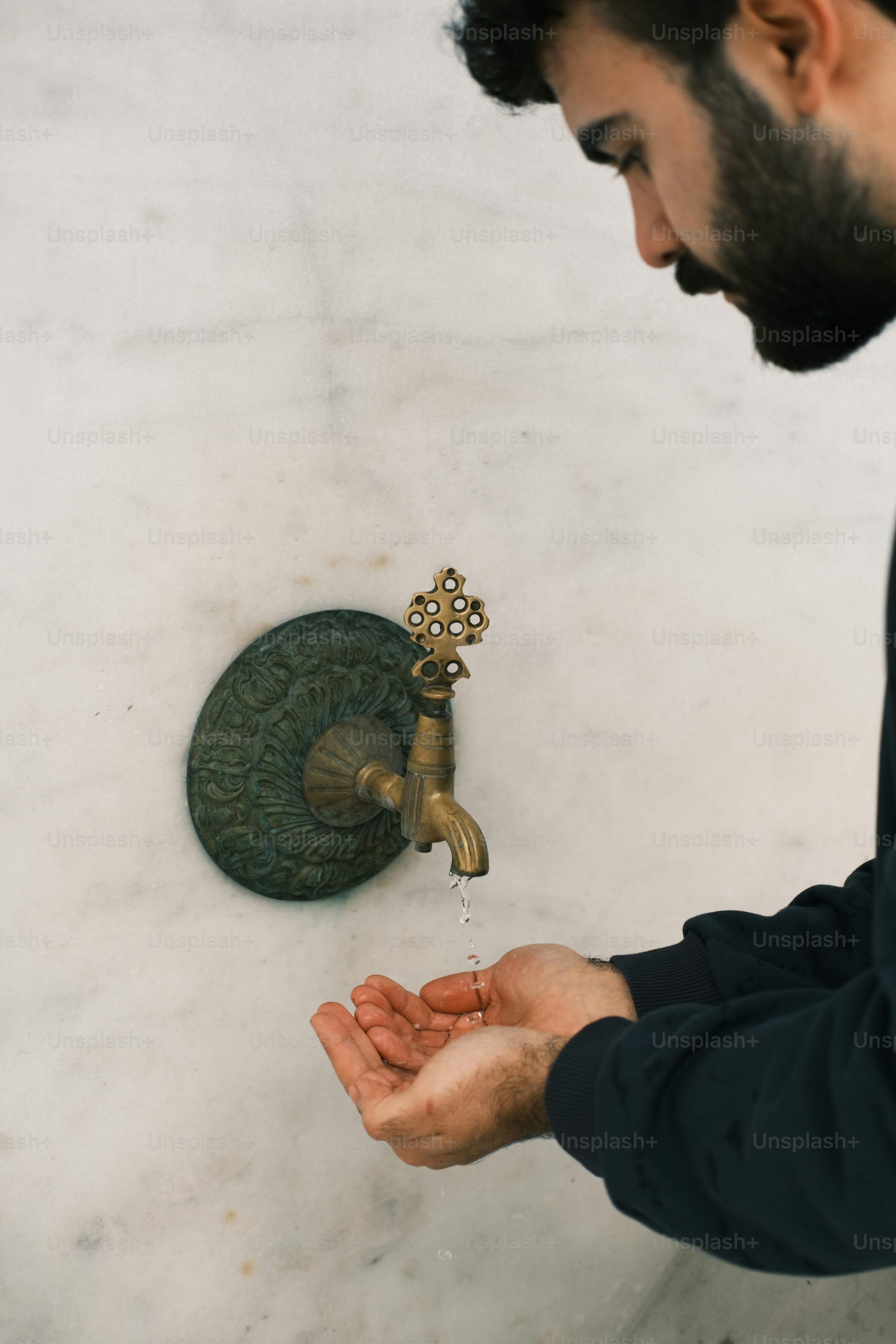 a man in a black jacket is washing his hands