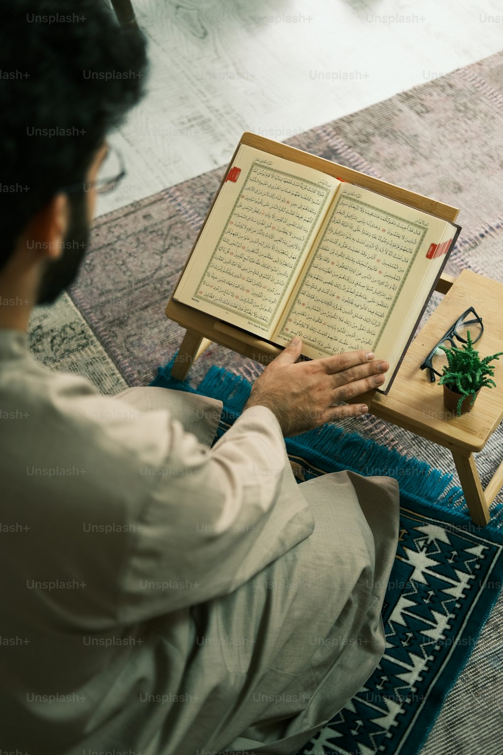 a man sitting on a rug reading a book
