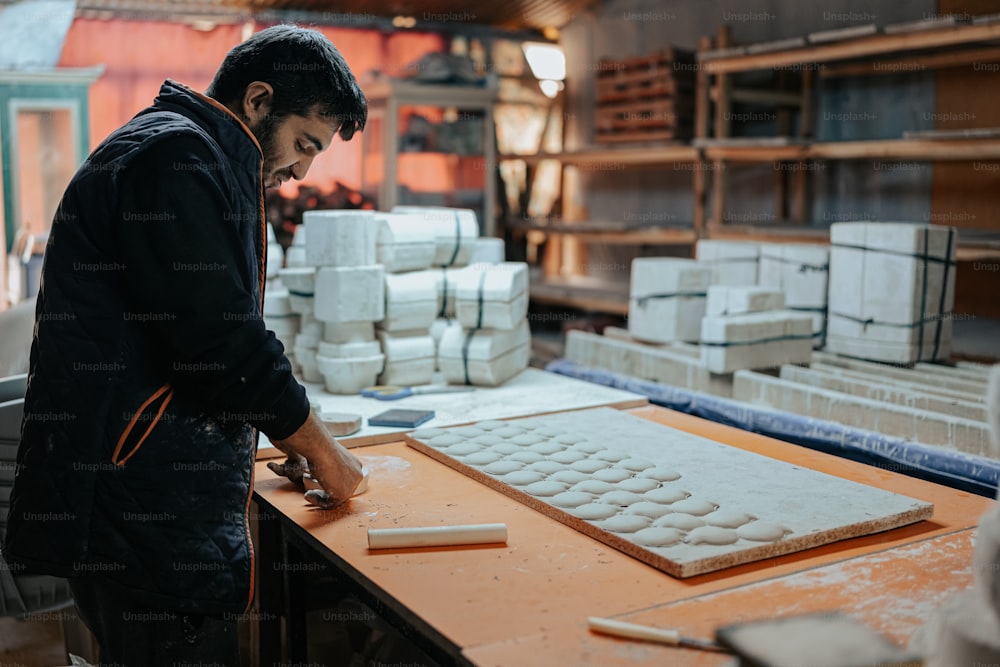 Ein Mann arbeitet in einer Fabrik mit einem großen Tablett mit Keksen