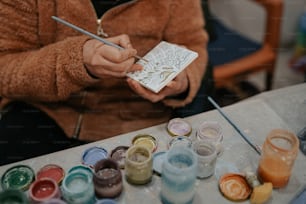 a person sitting at a table with paint and a brush