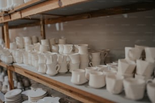 Un estante lleno de muchas tazas blancas y platillos