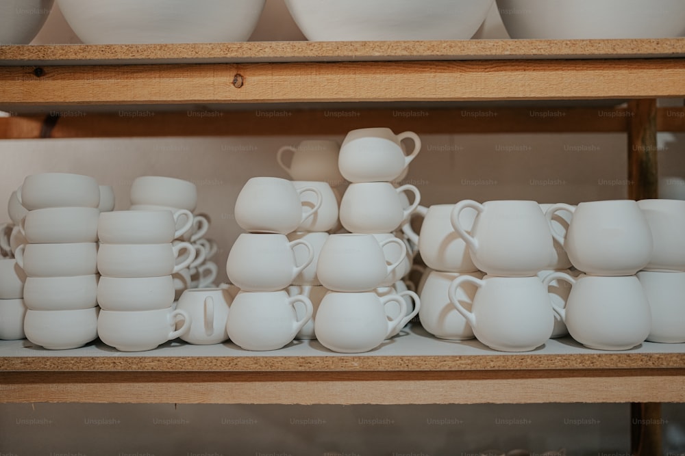 Un estante lleno de muchas tazas blancas y platillos