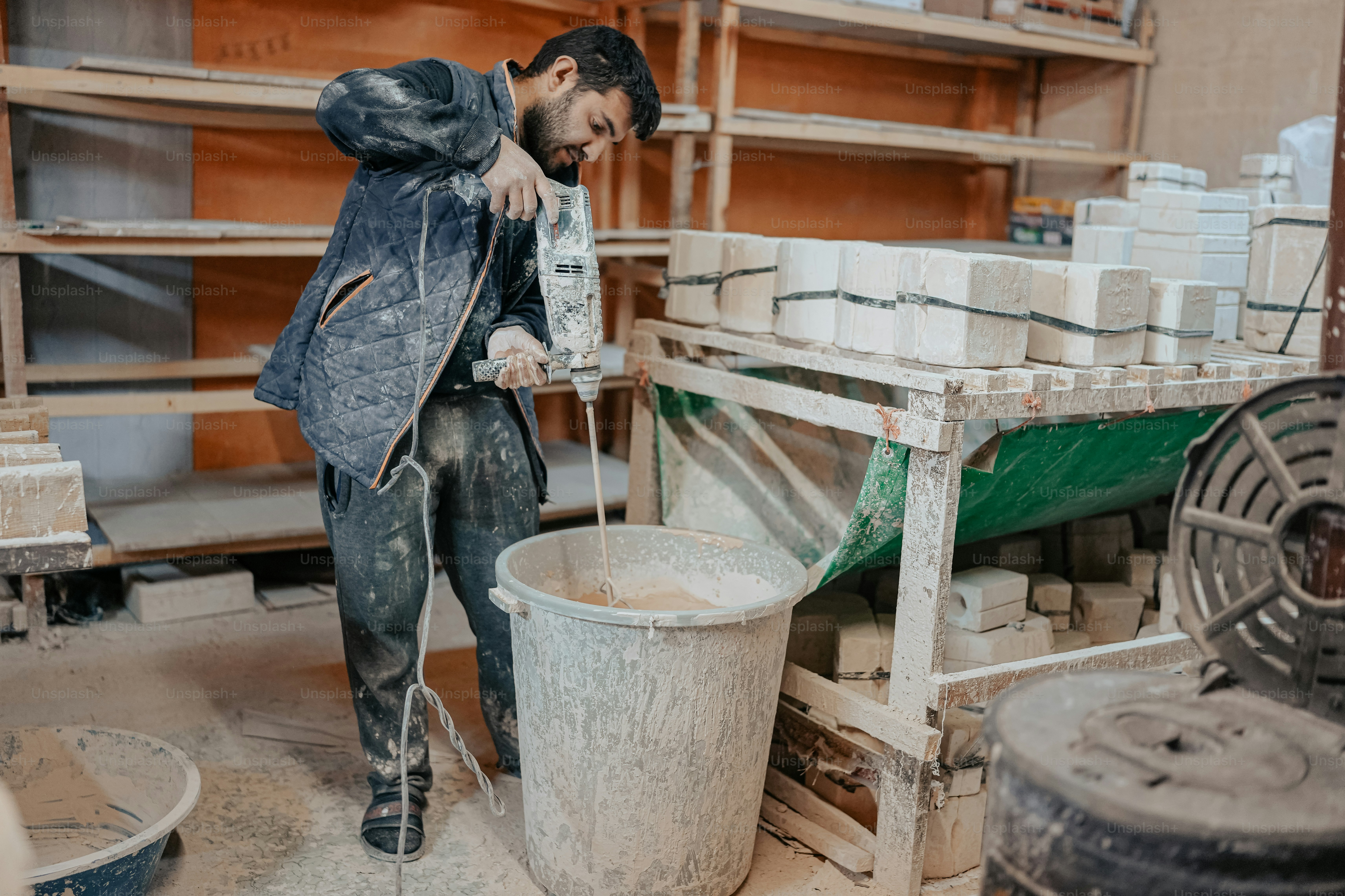 um homem de pé ao lado de um balde cheio de cimento
