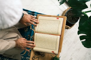 a person holding a book on top of a wooden table