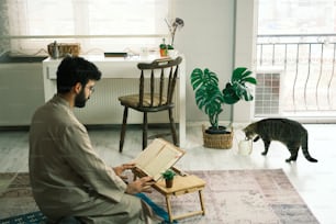 Un uomo seduto su una sedia di fronte a un gatto