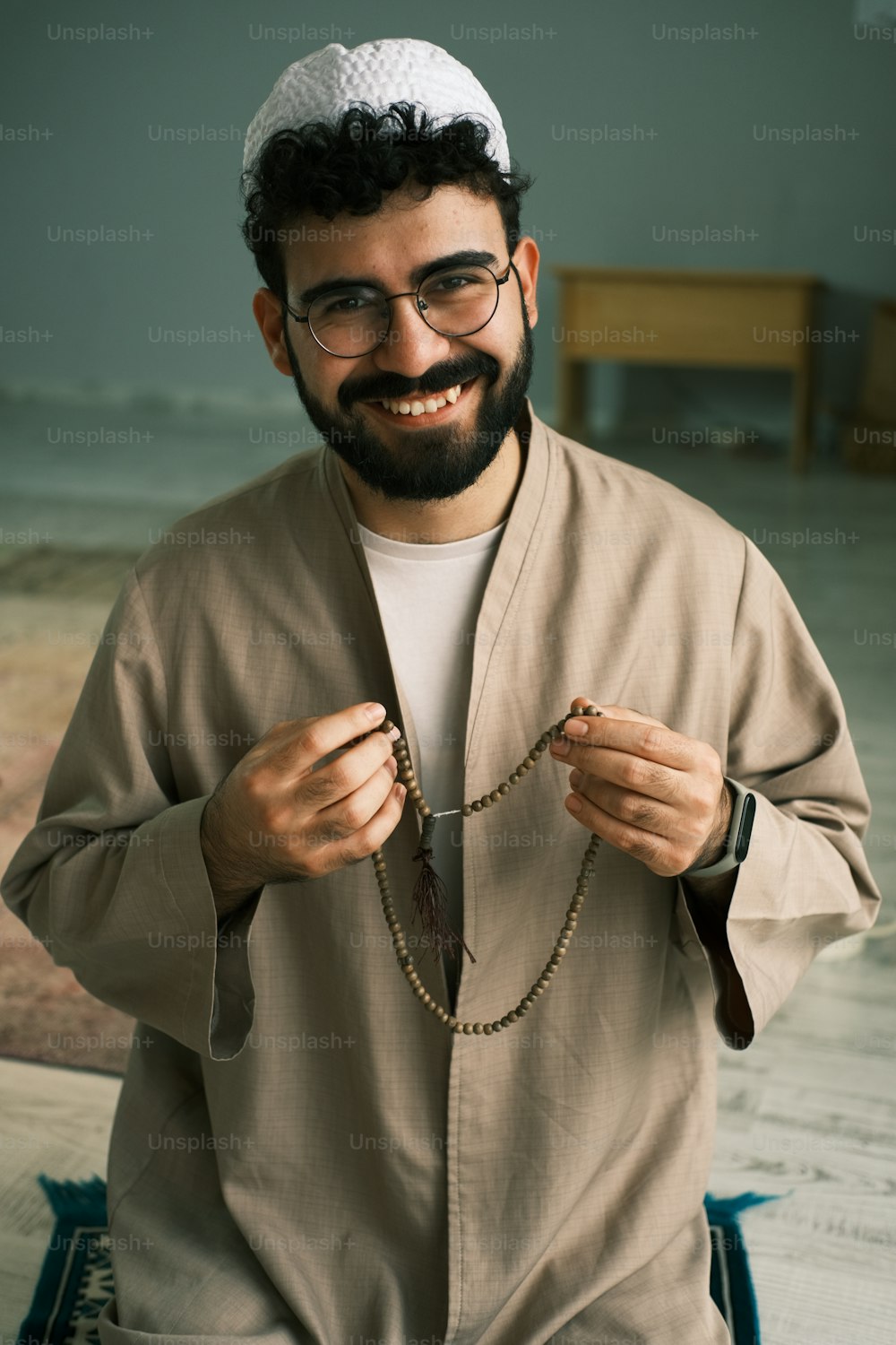 Un hombre con barba y gafas sosteniendo un rosario