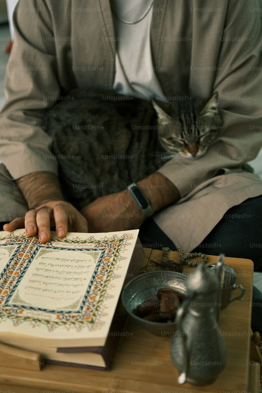 Ein Mann, der eine Katze hält, während er auf einem Tisch sitzt
