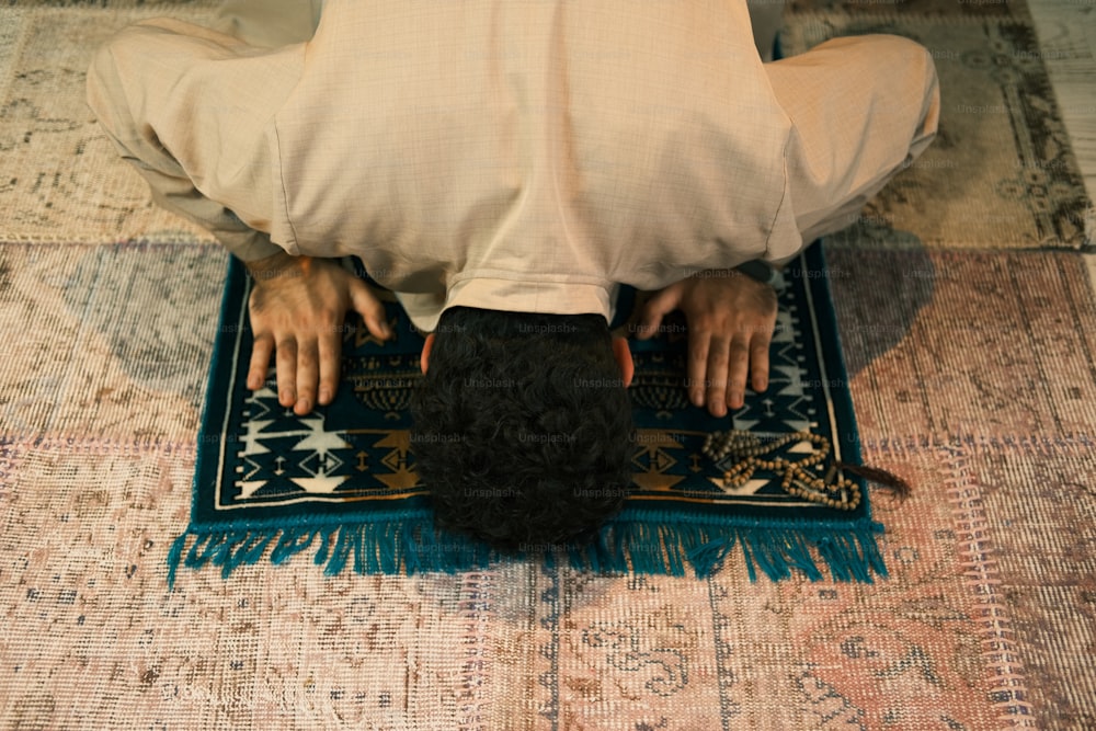 a man in a white shirt is sitting on a rug