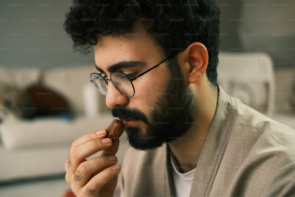 a man with a beard and glasses is eating something