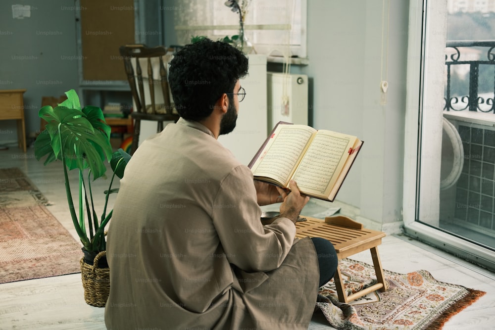Un hombre sentado en el suelo leyendo un libro