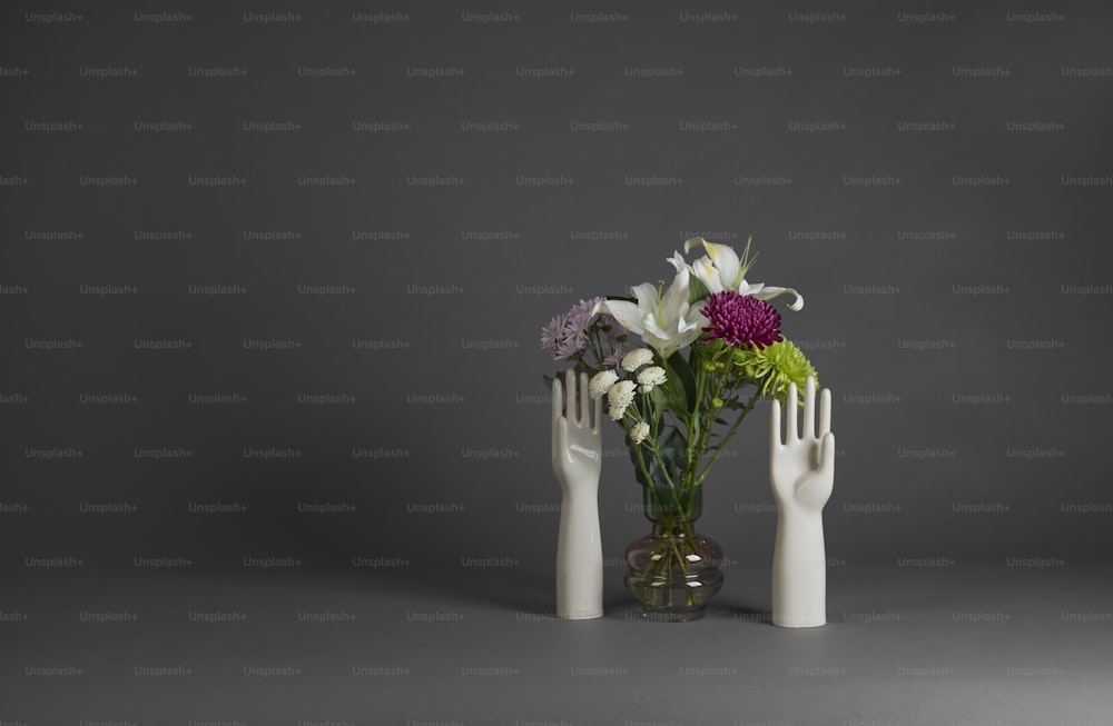 a vase filled with flowers and two white hands