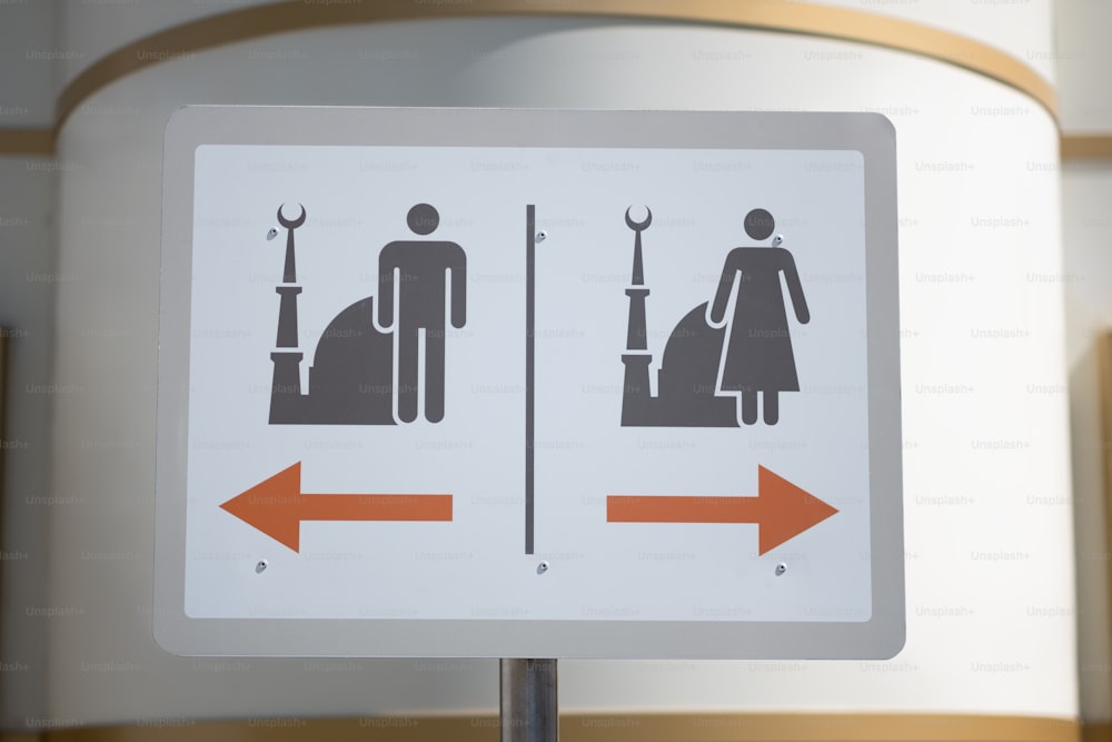 a white sign with an orange arrow pointing to a man and a woman