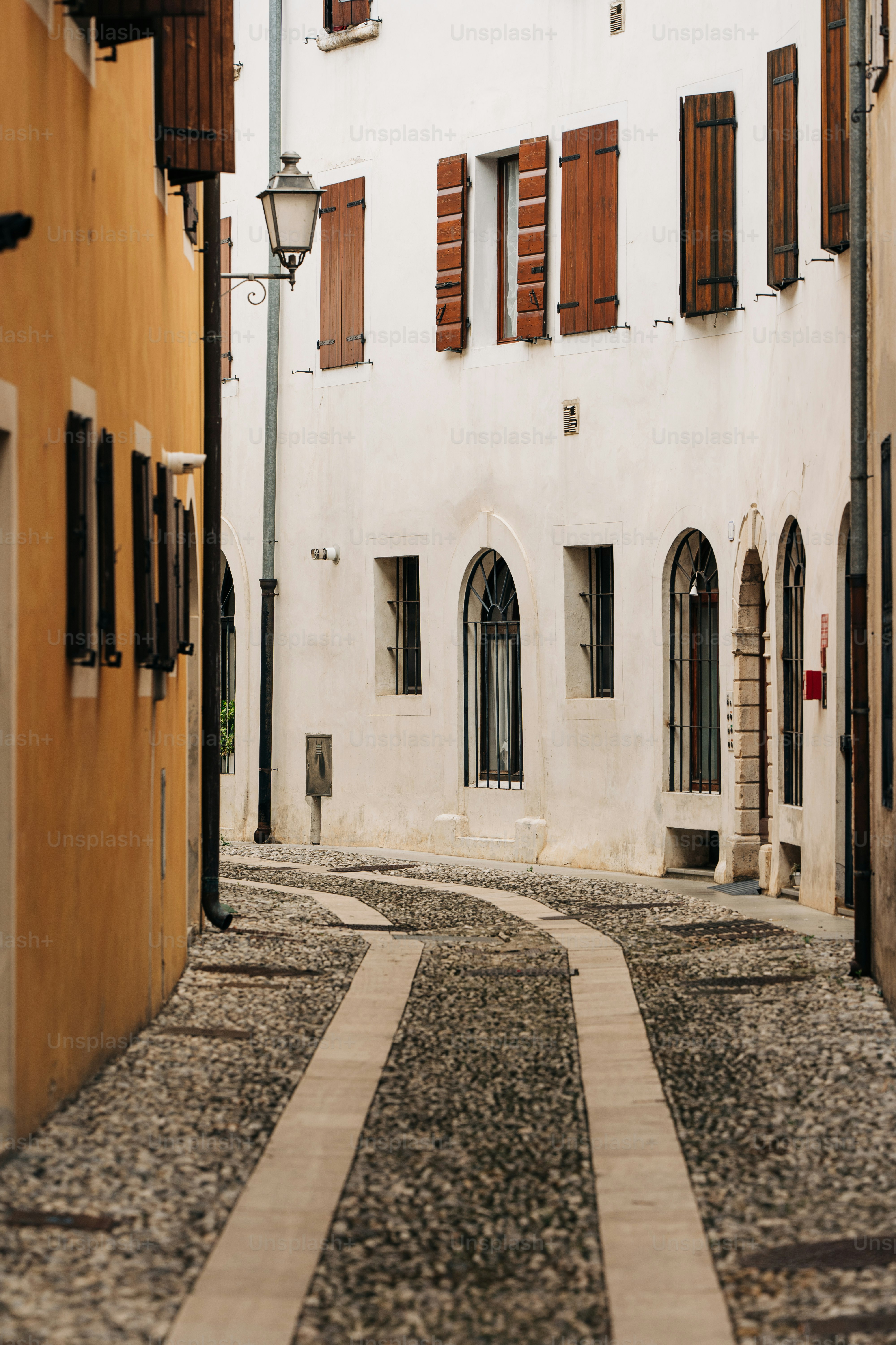 a narrow cobblestone street with a building in the background