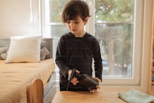 a young boy holding a sander and sanding on a table
