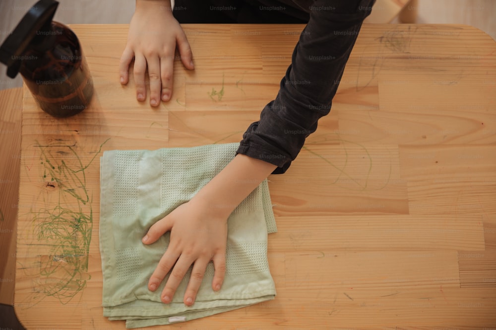 a person with their hand on a cloth on a table