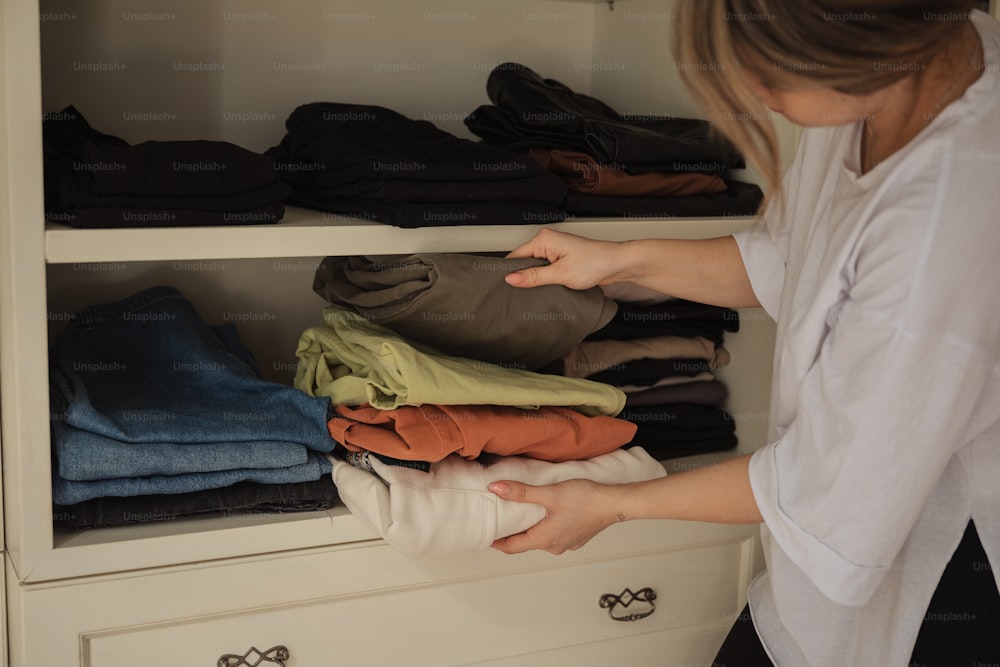 a woman standing in front of a closet filled with clothes