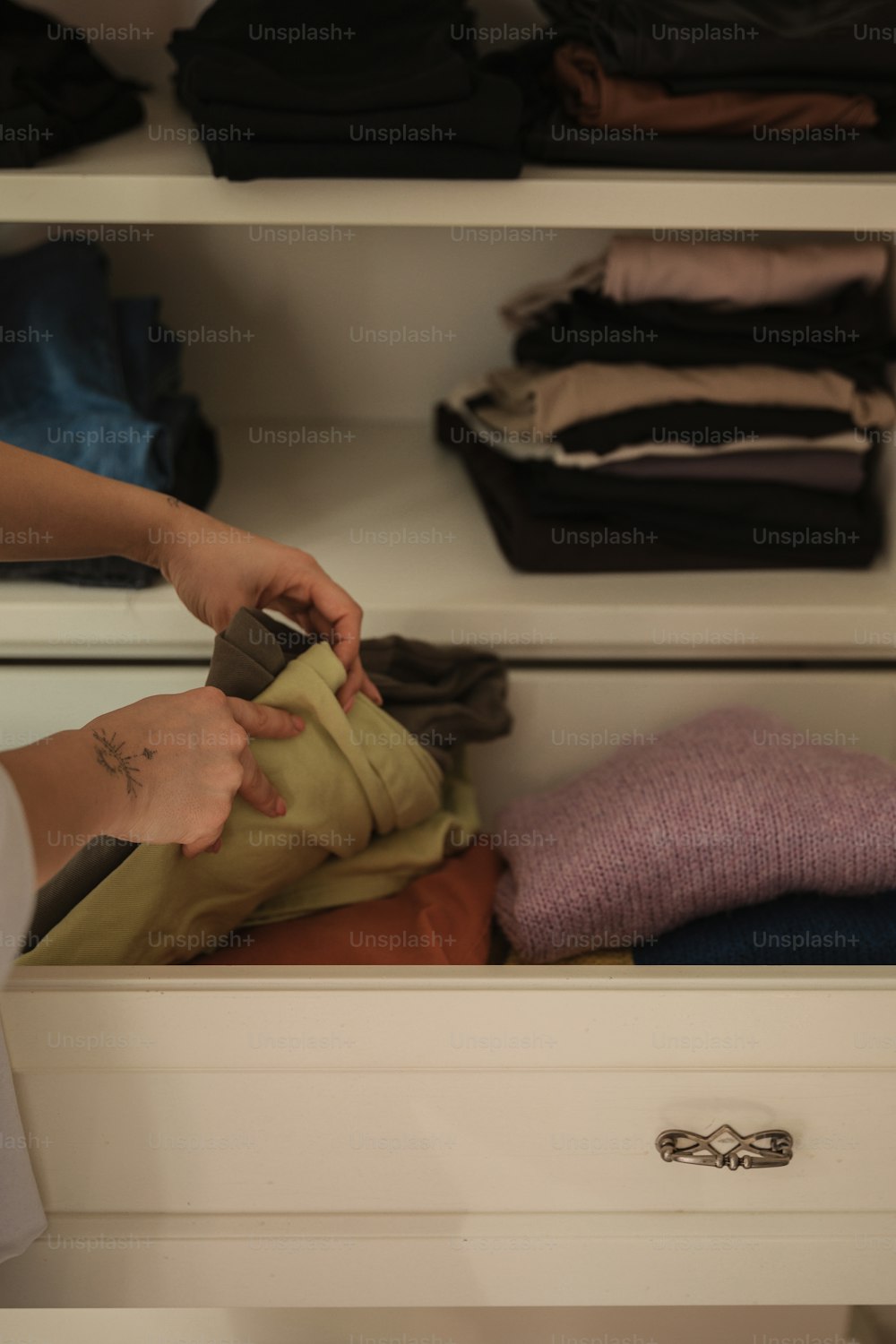 Eine Person legt Kleidung in einen Schrank