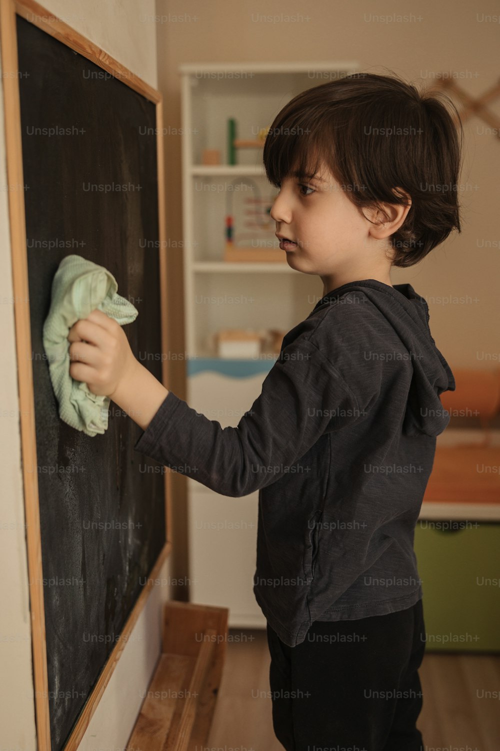a little boy that is standing in front of a chalkboard
