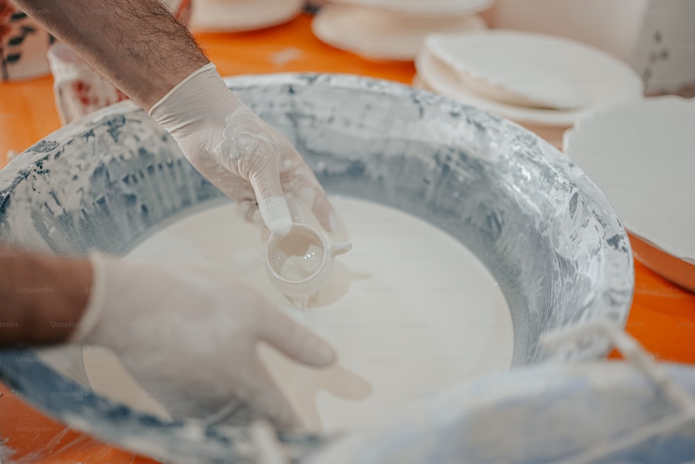 a person in white gloves and white gloves is mixing something in a bowl
