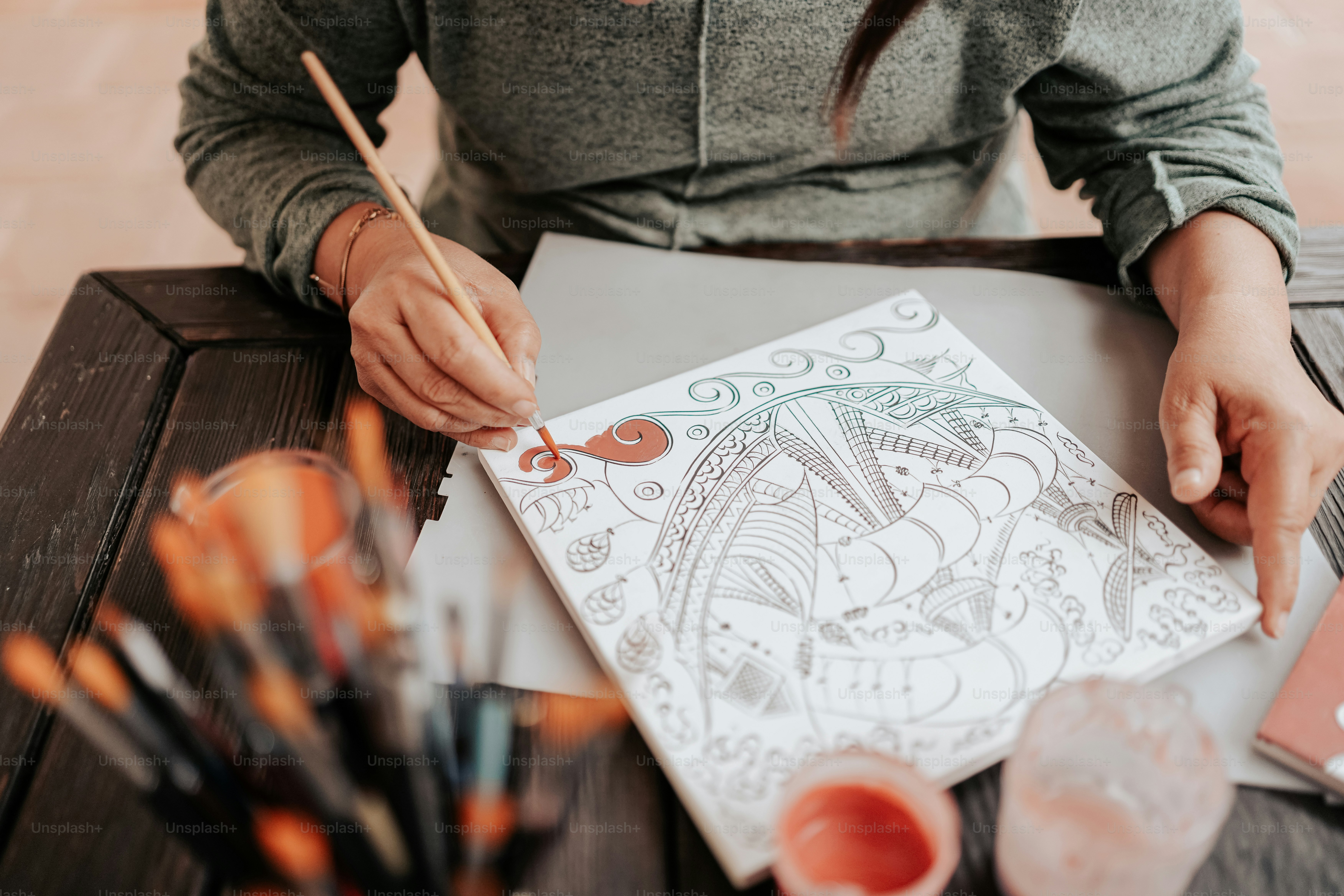 a woman sitting at a table drawing a picture