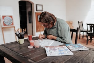 une femme assise à une table avec un cahier et un stylo