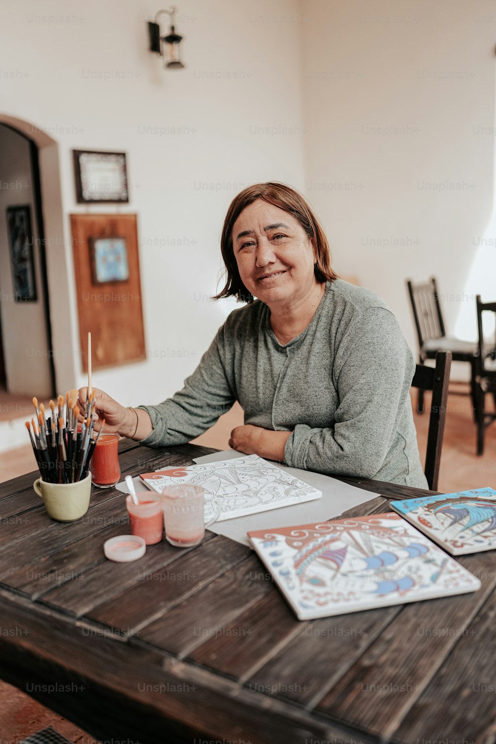 a woman is sitting at a table with some art supplies