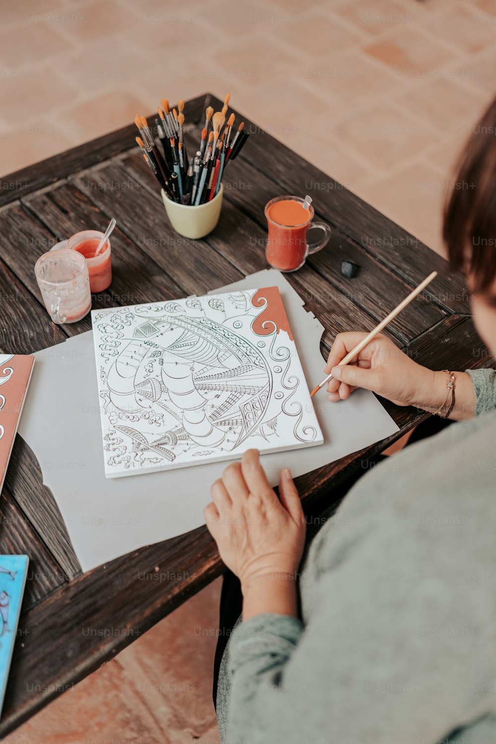 a woman sitting at a table drawing a picture
