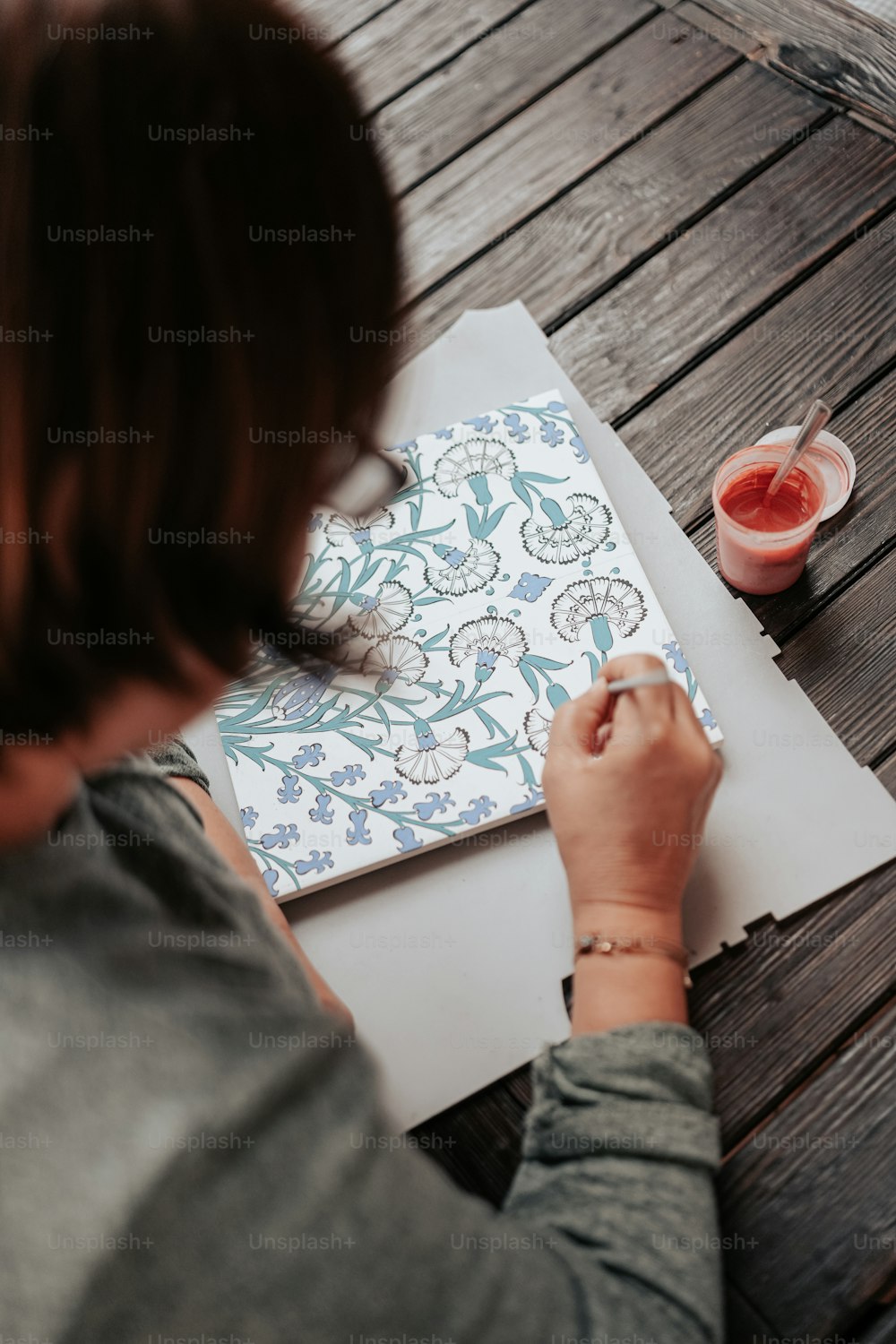 Una mujer sentada en una mesa dibujando en un pedazo de papel