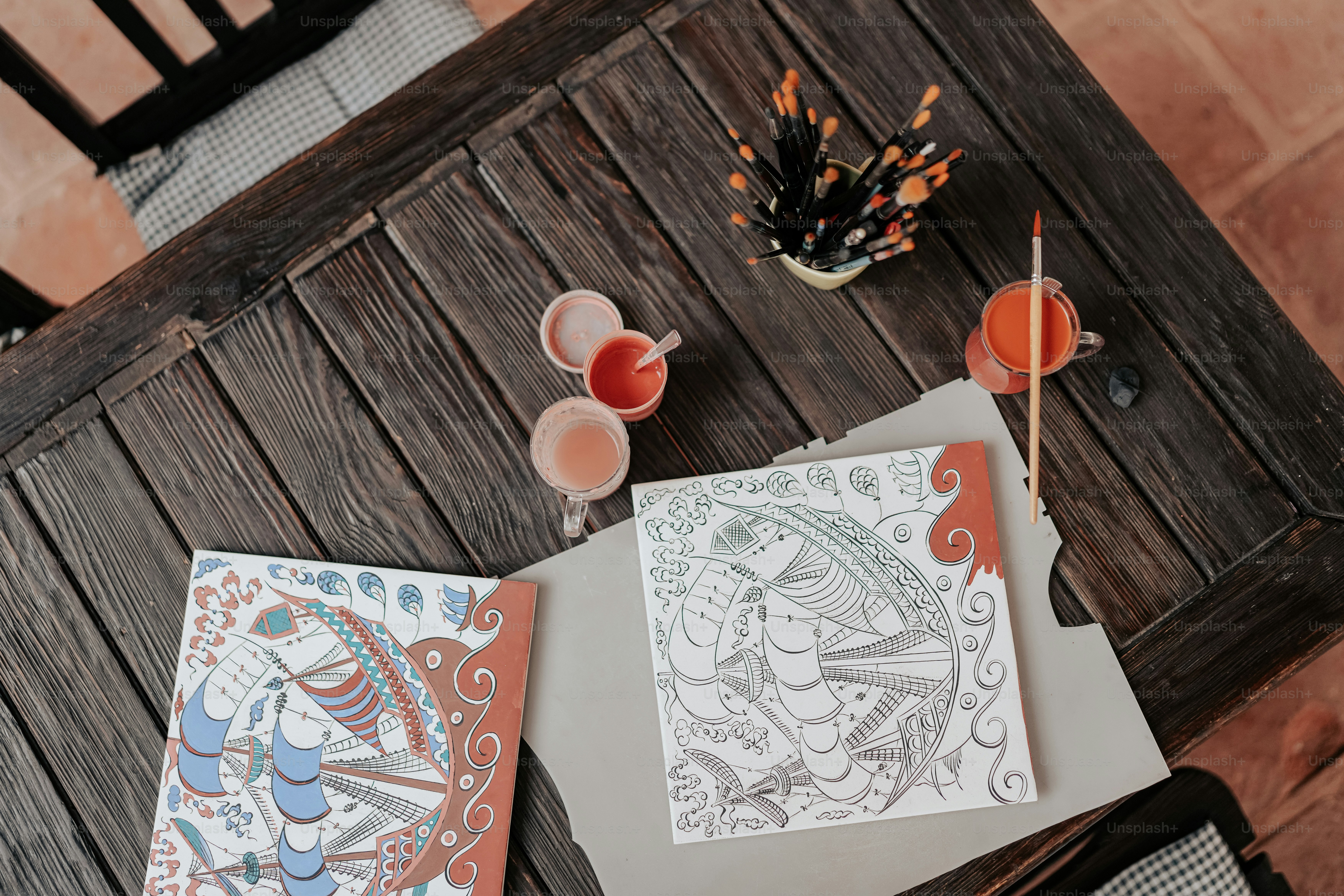 a table with two drawings and drinks on it