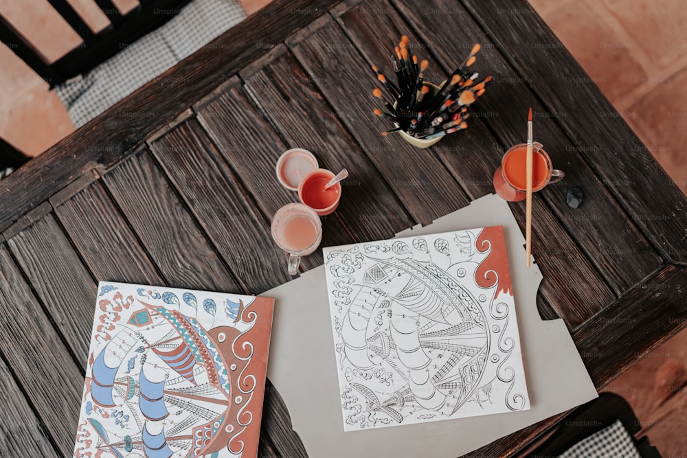 a table with two drawings and drinks on it