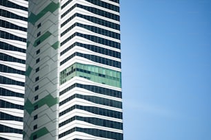 Ein hohes weiß-grünes Gebäude neben blauem Himmel