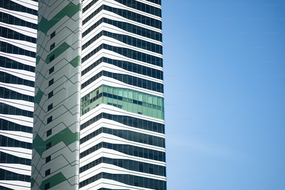 a tall white and green building next to a blue sky