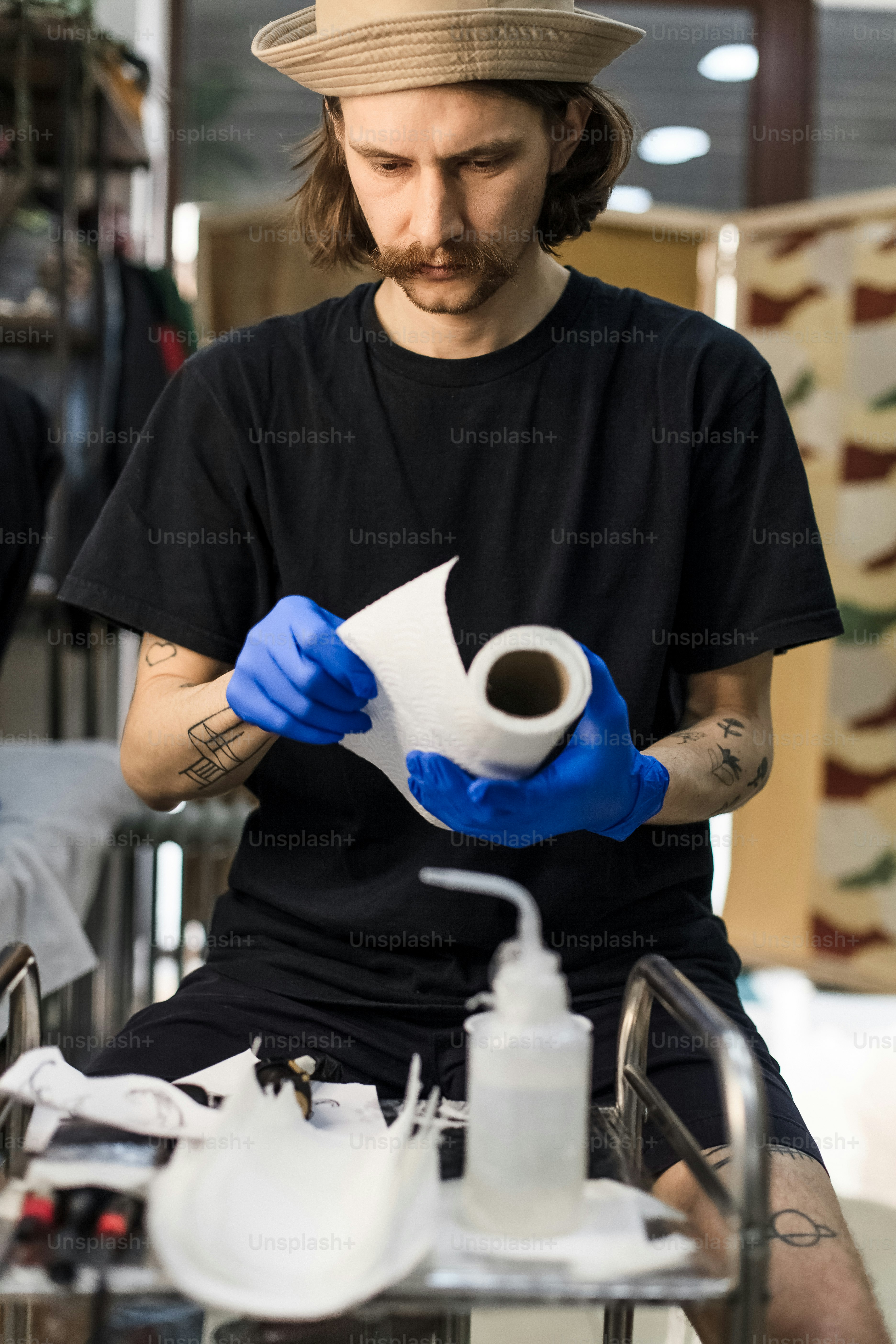 帽子と青い手袋をはめた男がトイレットペーパーのロールを持っている