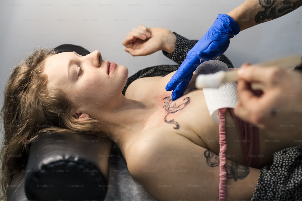 une femme se faisant tatouer par un tatoueur