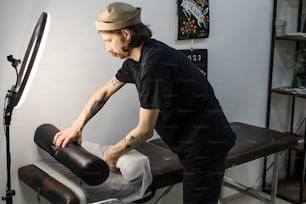 a man in a black shirt and hat waxing a black object