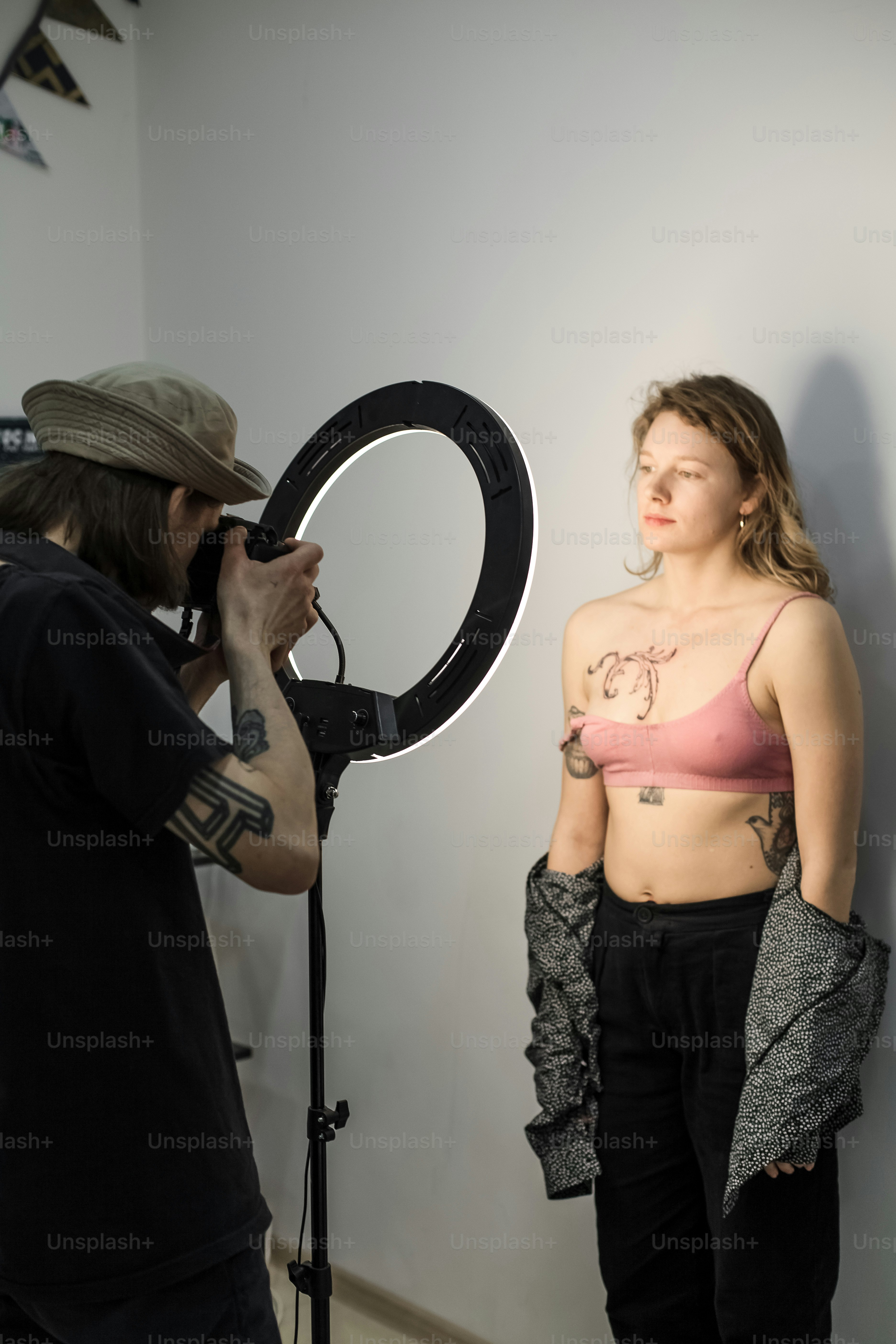 une femme en soutien-gorge rose et un homme avec un appareil photo